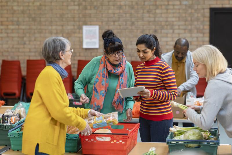 A group of 4 women, mixed ages and ethnicities at a food bank organising donation