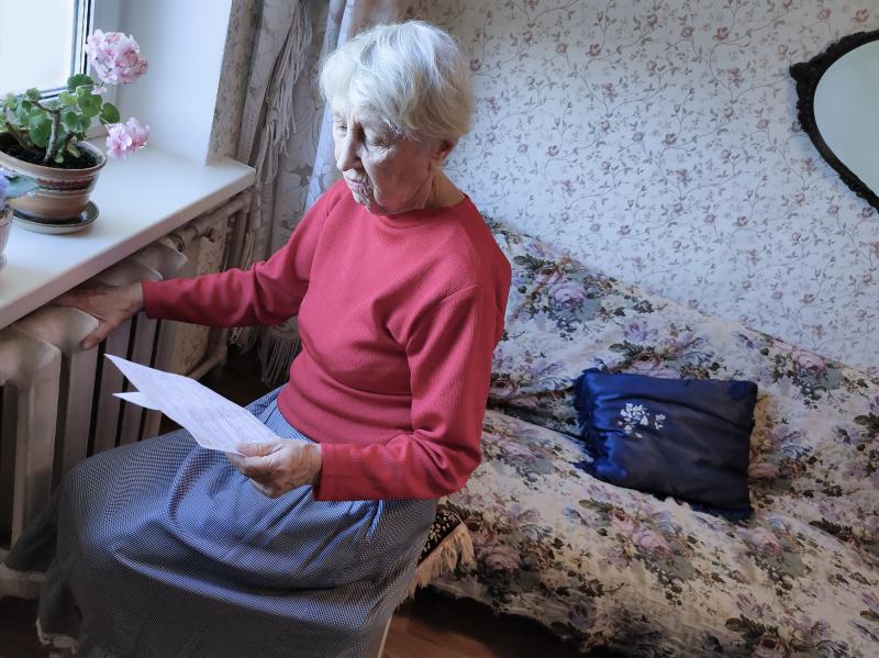 Senior woman feeling her radiator and reading her gas bill