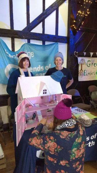 Campaigners running a stall with a pink doll's house