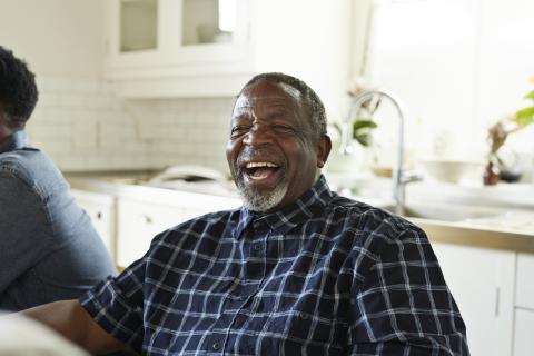 Happy senior man laughing while sitting at home