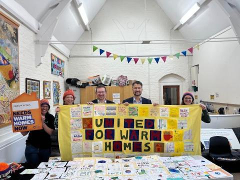 Manchester Friends of the Earth show their MPs their quilt on the Warm Homes Day of Action