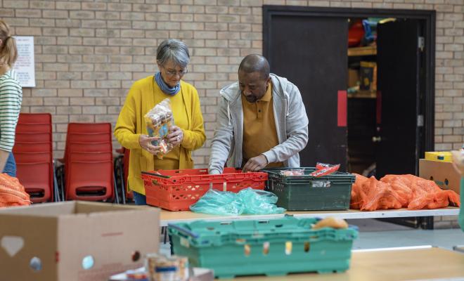2 volunteers are sorting out food stock at a foodbank