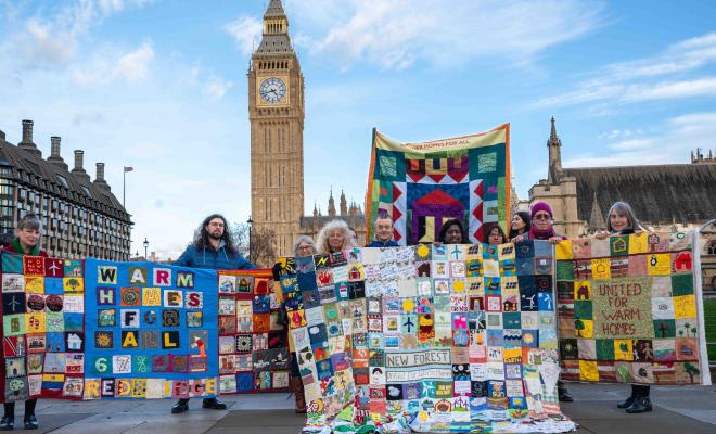Campaigners stand in front of Big Ben holding community quilts for warm homes
